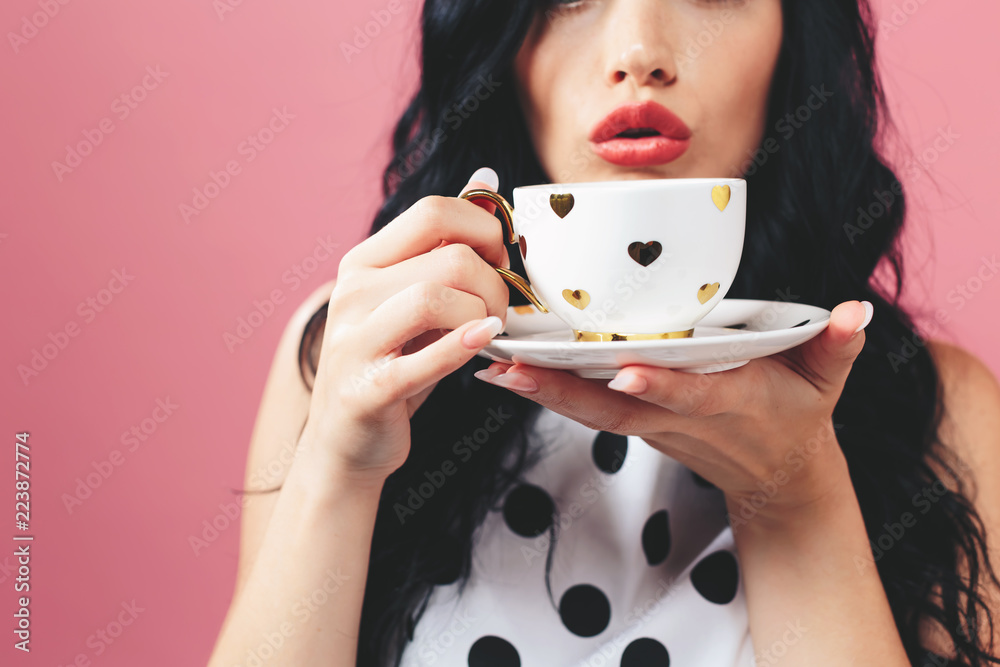 Young woman drinking coffee on a solid background