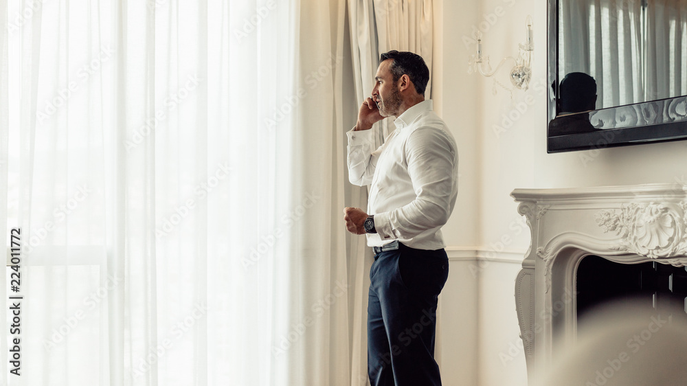 Businessman speaking on mobile phone in hotel room