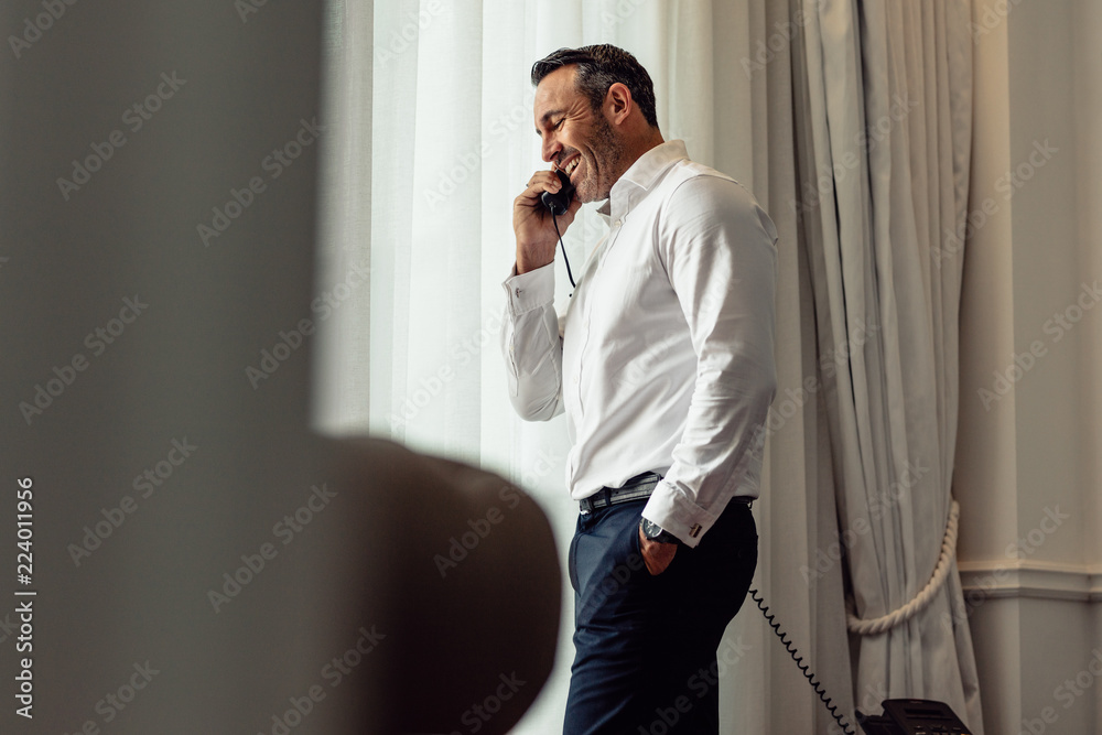 Businessman talking on phone from hotel room