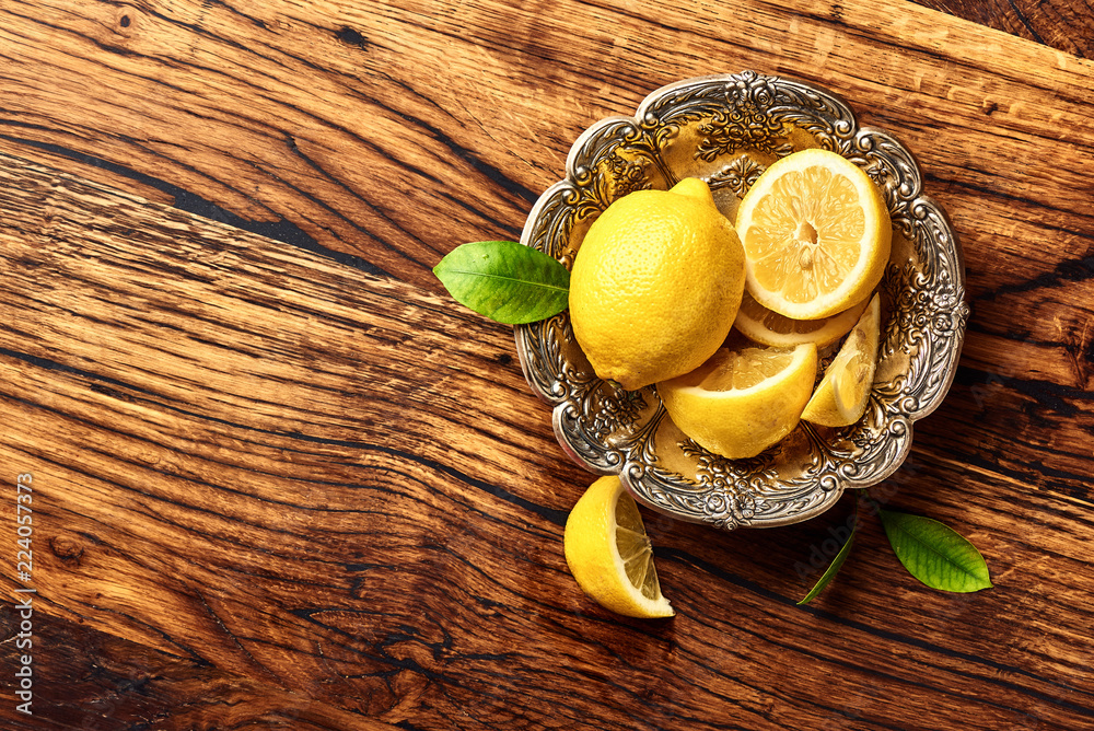 Lemons with leaves on oak wooden table. Copy space for design or text. Top view of fruits.