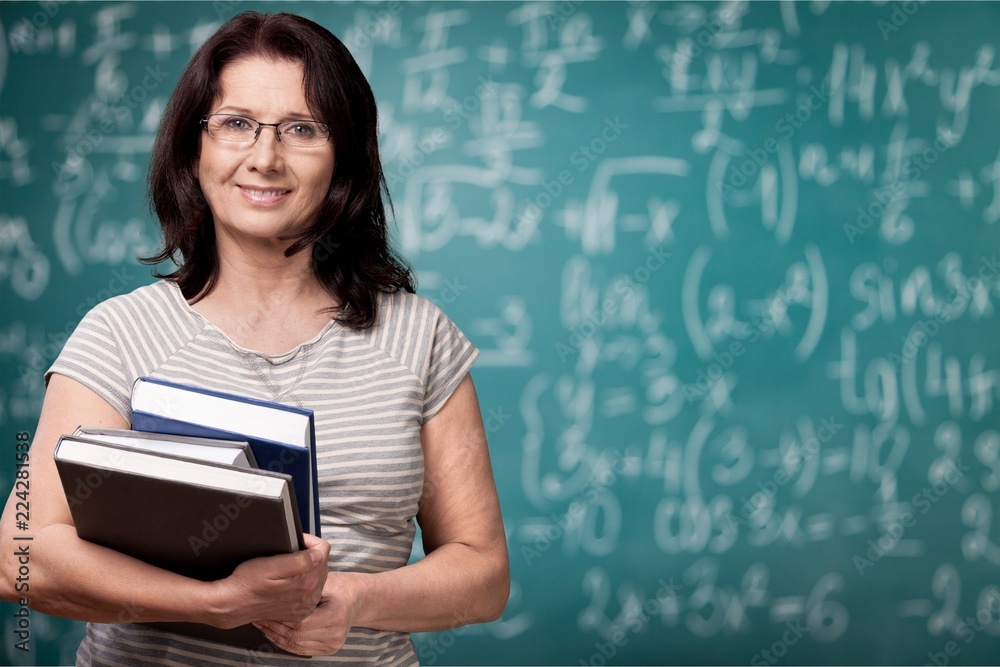 Mature woman teacher with books on background