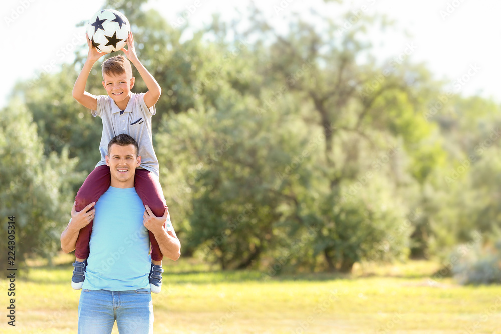 Little boy and his dad with soccer ball outdoors