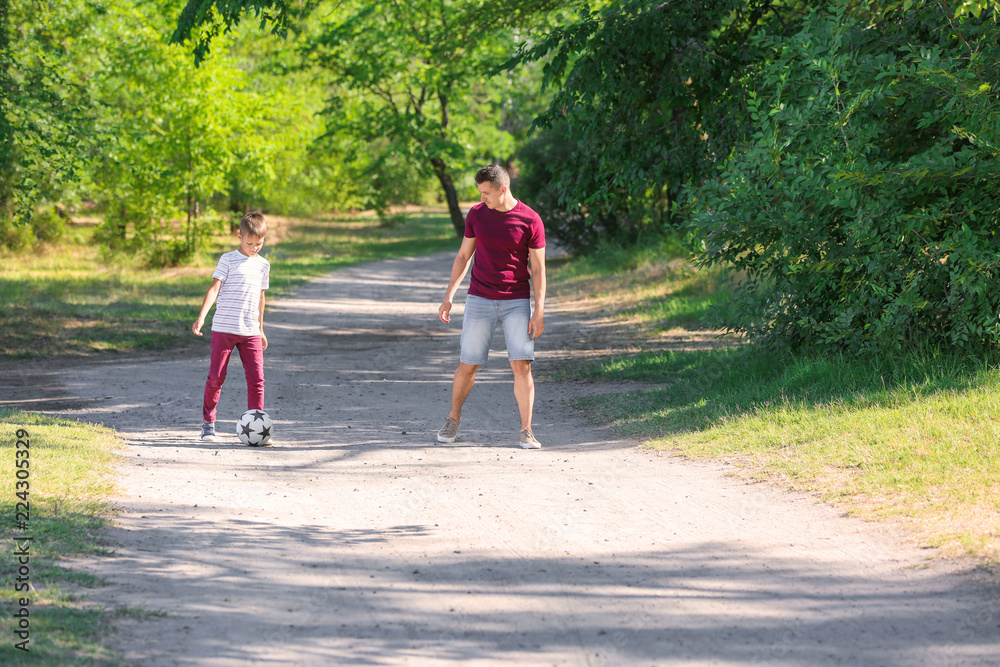 Little boy with his dad playing football outdoors