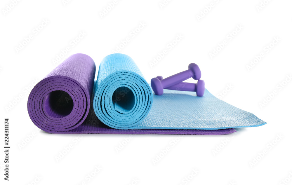 Different yoga mats with dumbbells on white background