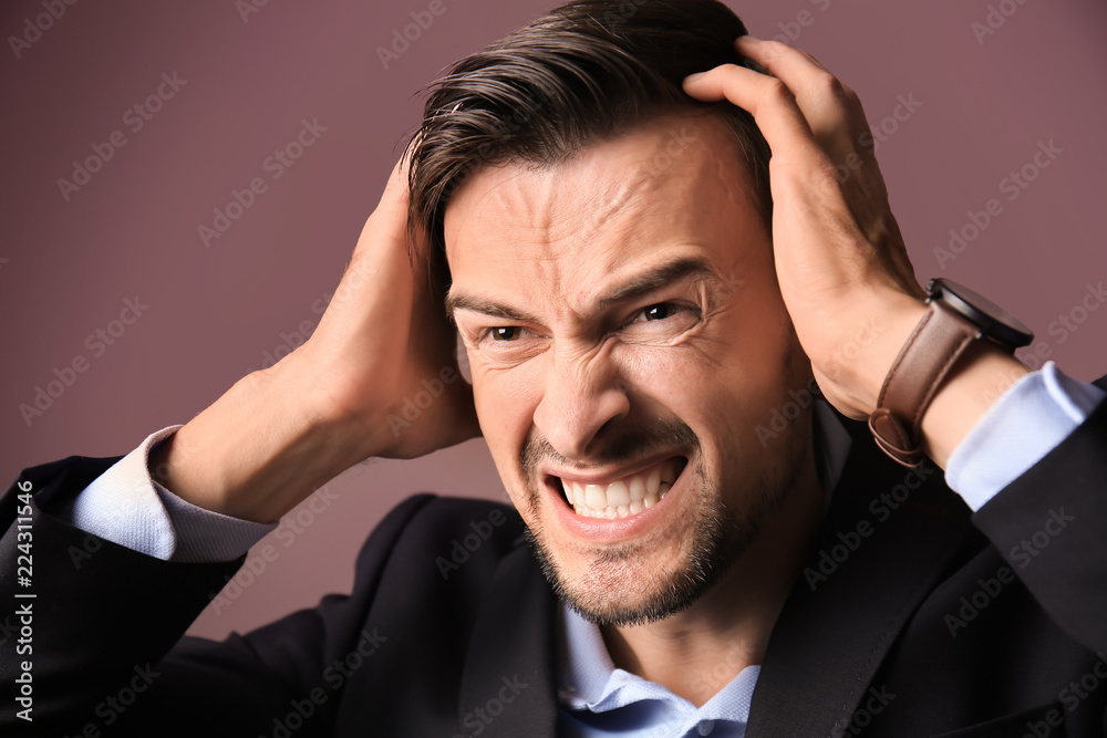 Handsome stressed businessman on color background