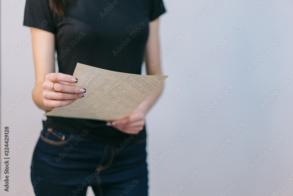 信在一个白人背景的年轻女孩手中。一个穿着牛仔裤和T恤的女孩站在我面前。