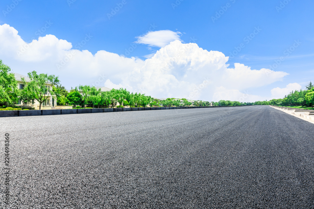 城市郊区的沥青道路和带公寓楼的树林