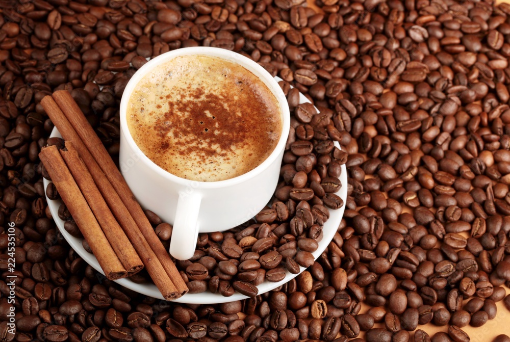 Cappuccino or latte surrounded by coffee beans and cinnamon