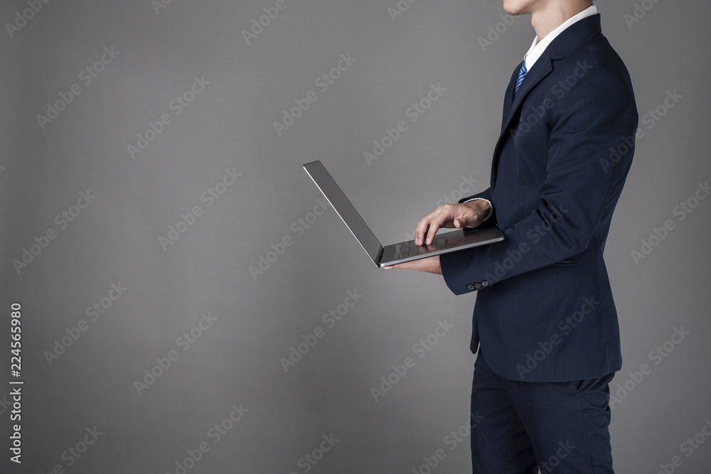 Business man is using laptop ,grey background in studio