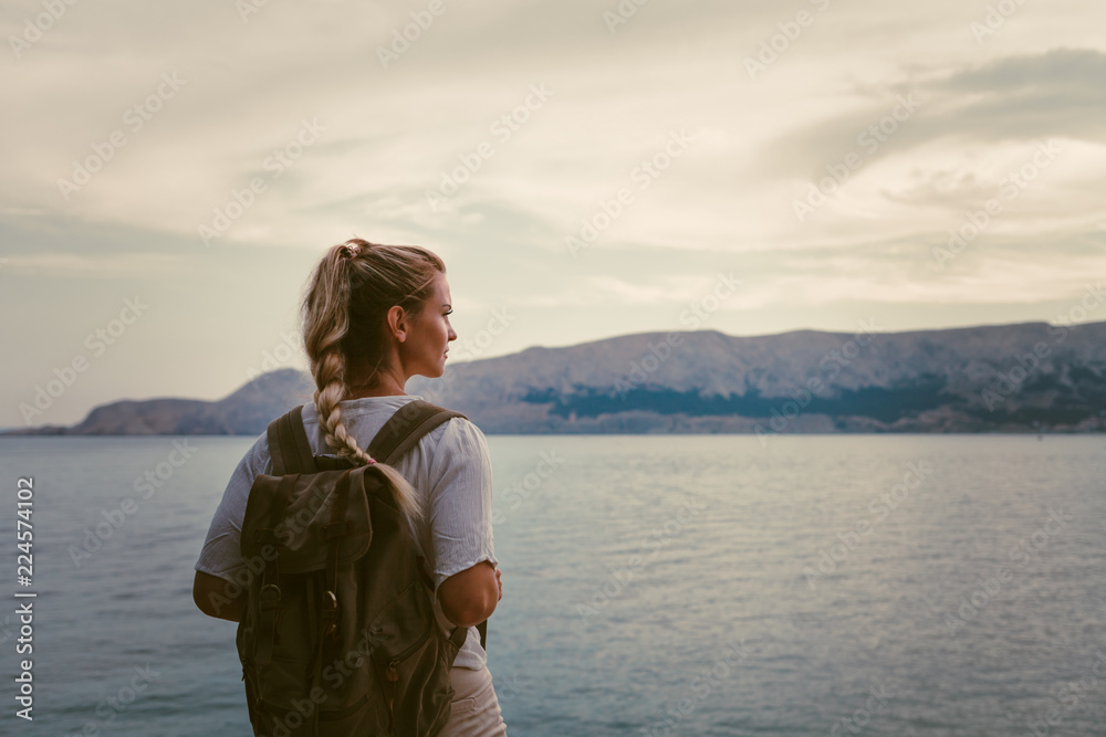 背着背包徒步旅行并欣赏海湾景色的旅游女性