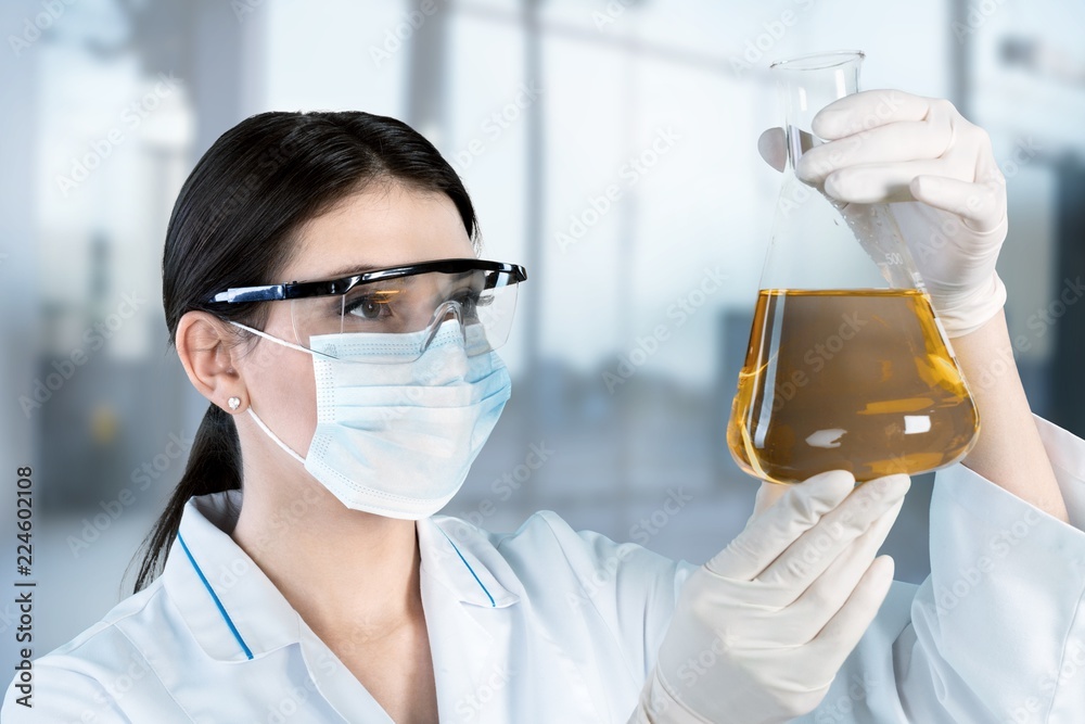 Young female scientist holding flask with reagent