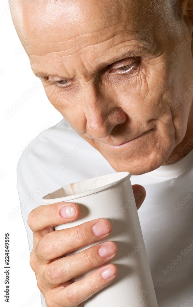 Close-up of senior man in white shirt holding cup isolated on