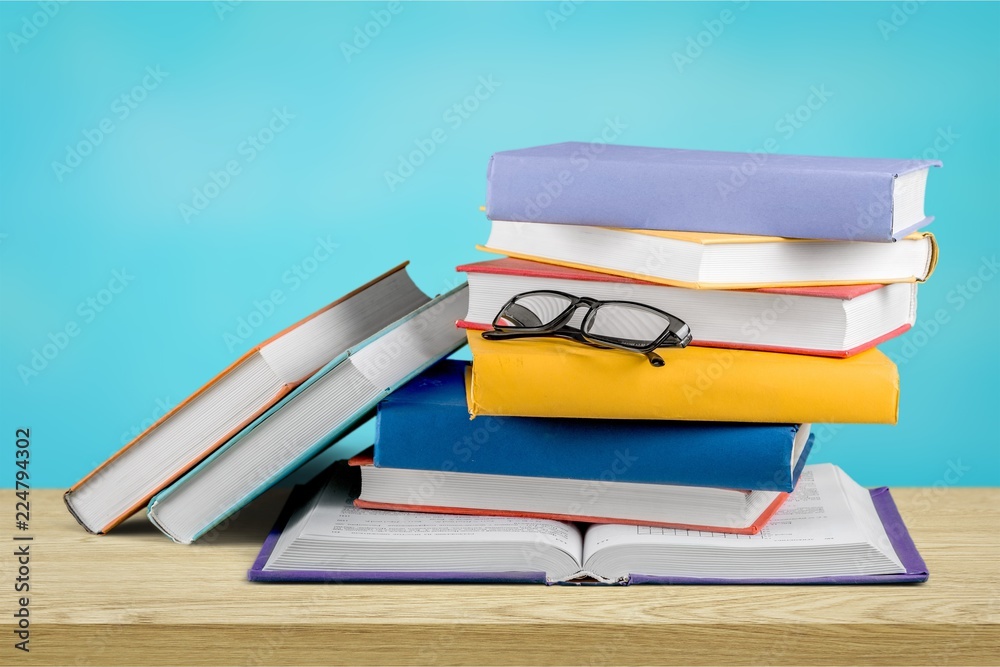 Heap of books with glasses on wooden