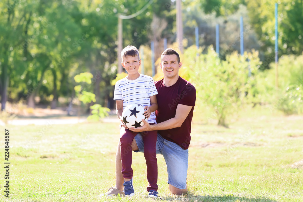 Little boy and his dad with soccer ball outdoors