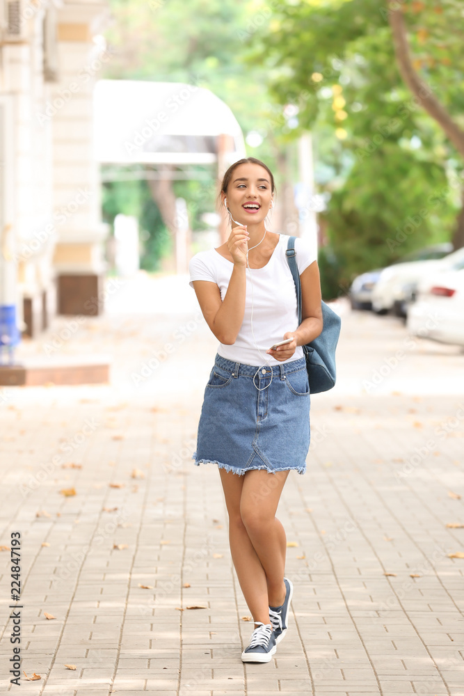 美丽的年轻女子在户外听音乐