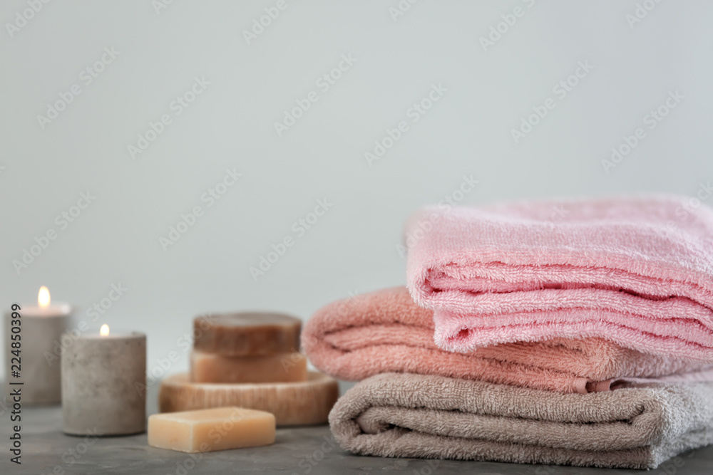 Clean folded towels on table with burning candles