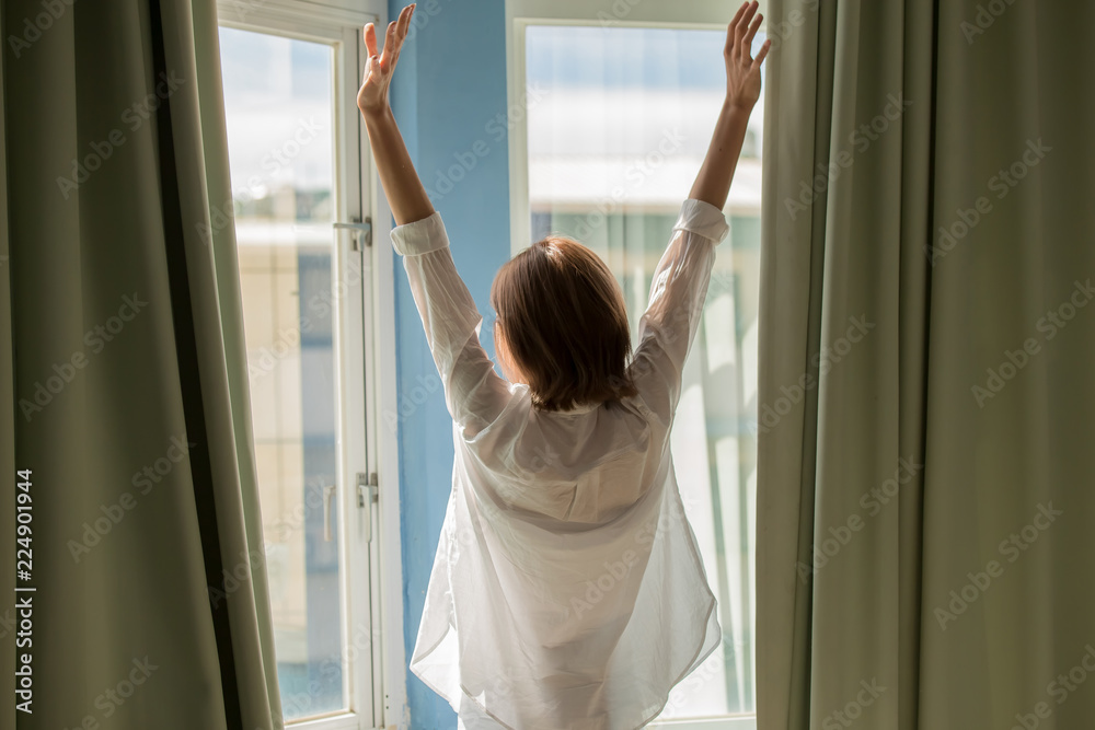 woman opening curtains