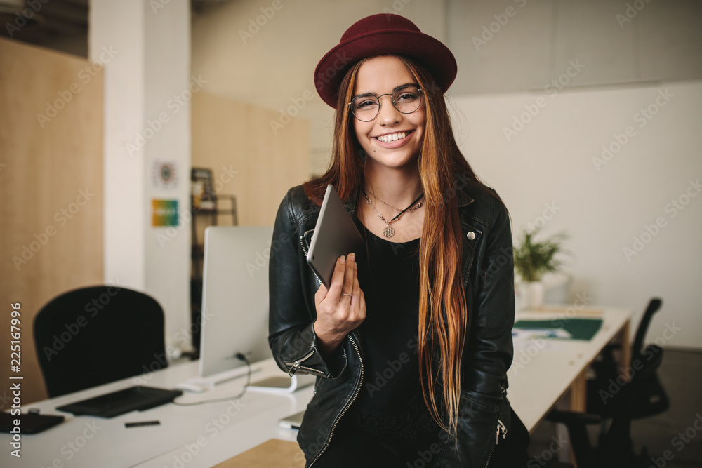 Women entrepreneur standing in office holding a tablet pc