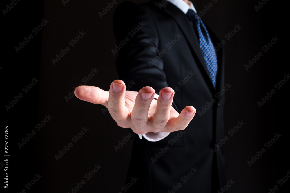 Man in a business suit holding his hand out and showing something