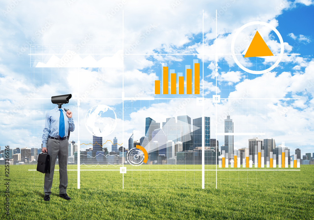 Camera headed man standing on green grass against modern cityscape