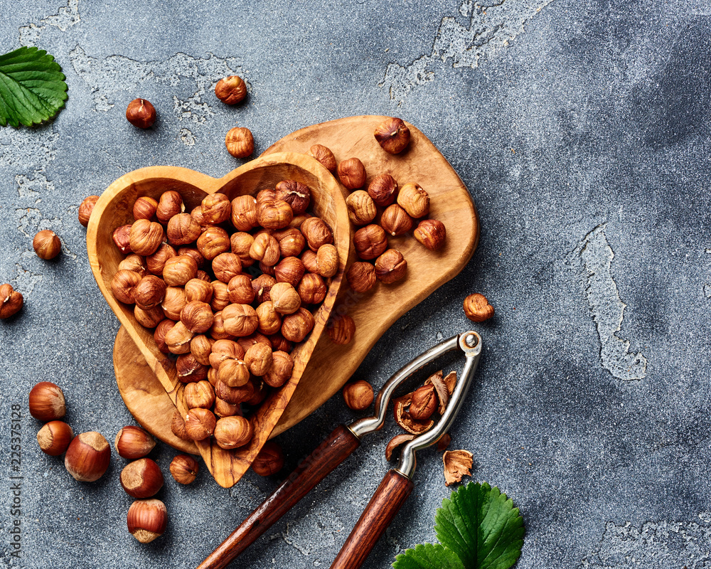 Hazelnuts with nutcracker on gray background. Top view of nuts.