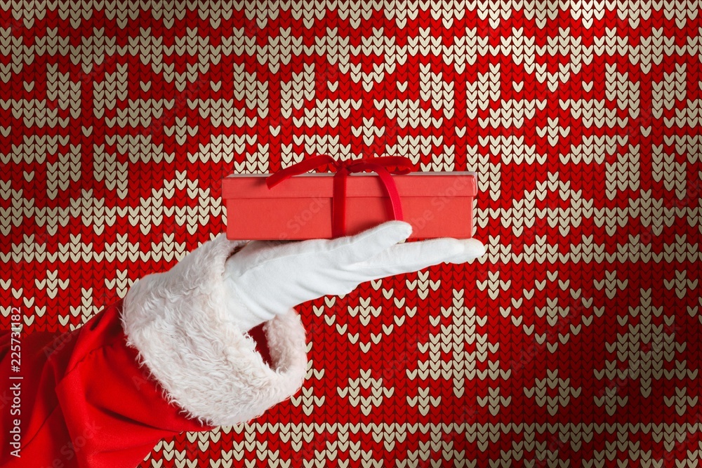 Composite image of santa claus holding a gift box in hand