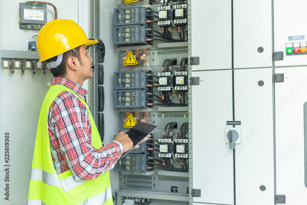 Asian maintenance engineers inspect relay protection system with laptop computer. Bay control unit. 