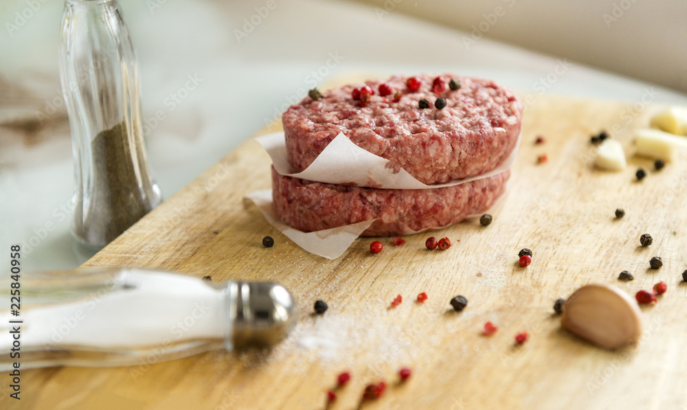 2 beef raw cutlets on a wooden Board with spices, meat, garlic, pepper, salt in a salt shaker