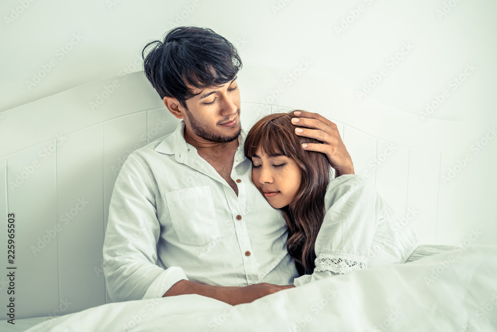 Happy young couple relaxing in the home bedroom.