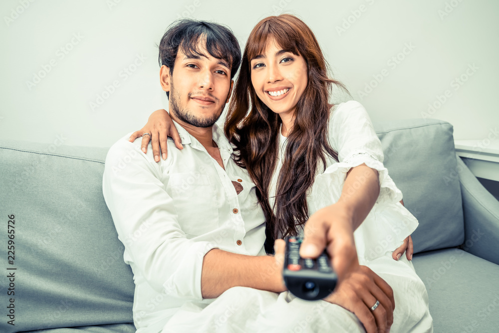 Happy young couple watching TV in living room.