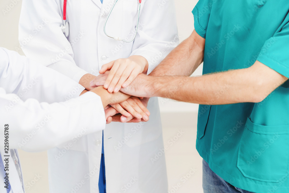 Doctor, surgeon and nurse join hands together.