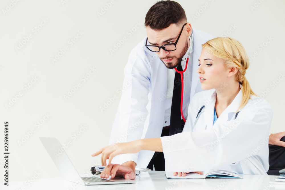 Doctor at hospital works on computer with partner.