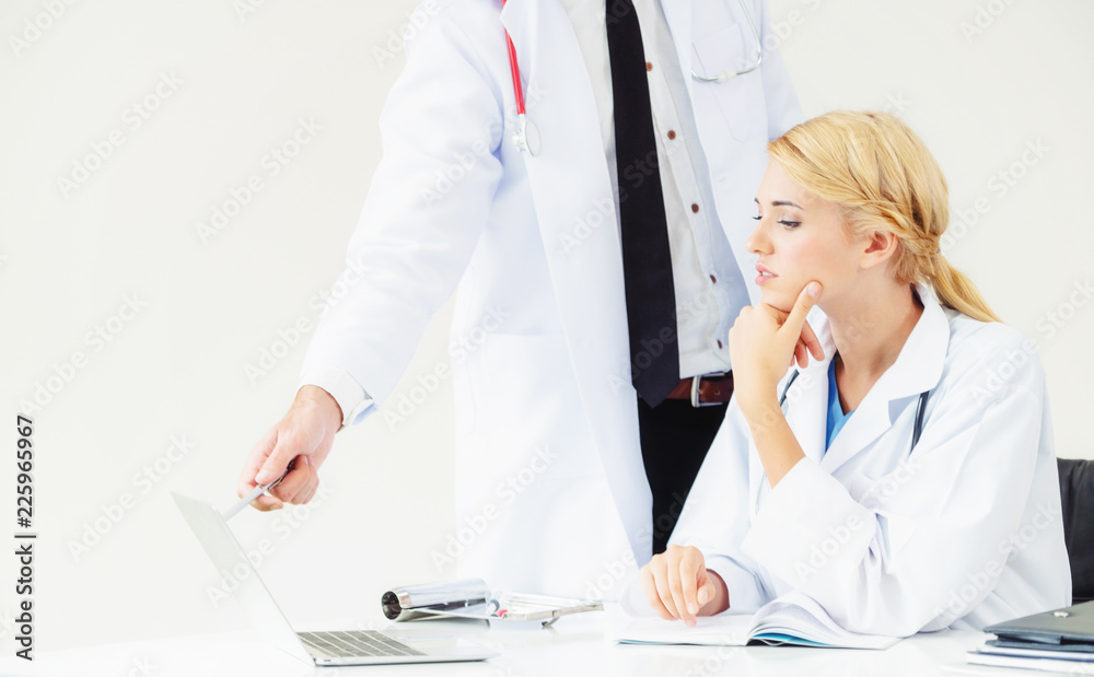 Doctor at hospital works on computer with partner.