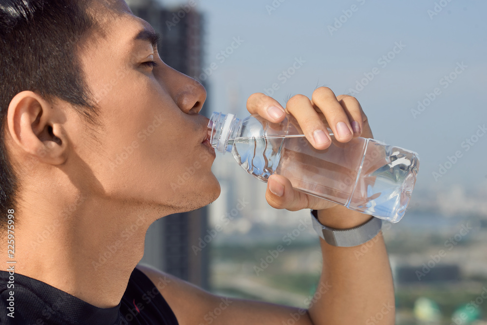 一名男子在外面用瓶子喝水的特写