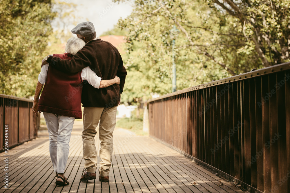 Senior couple in warm clothing walking together in park