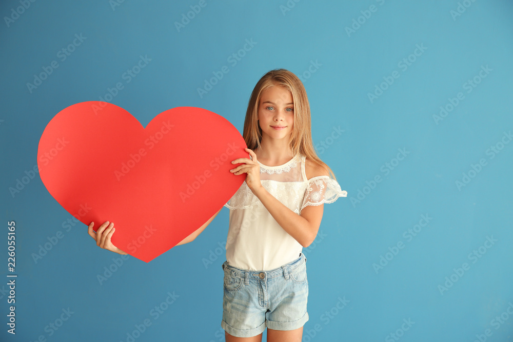 Cute little girl with paper heart on color background