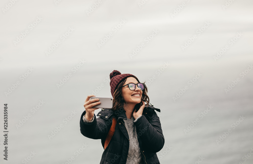 微笑的女旅行者对着大海自拍