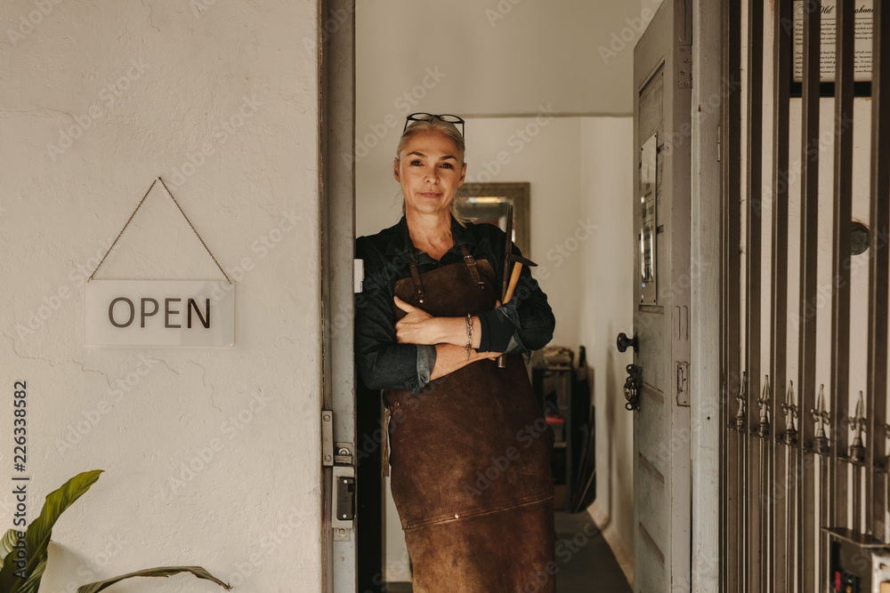 Female goldsmith standing at workshop door