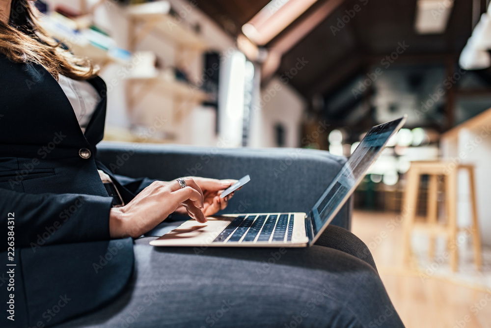 Close-up image of female person using laptop and credit card for online shopping.