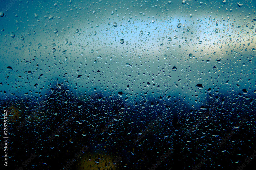 raindrops are on the window glass of a house on a blue background. Close-up