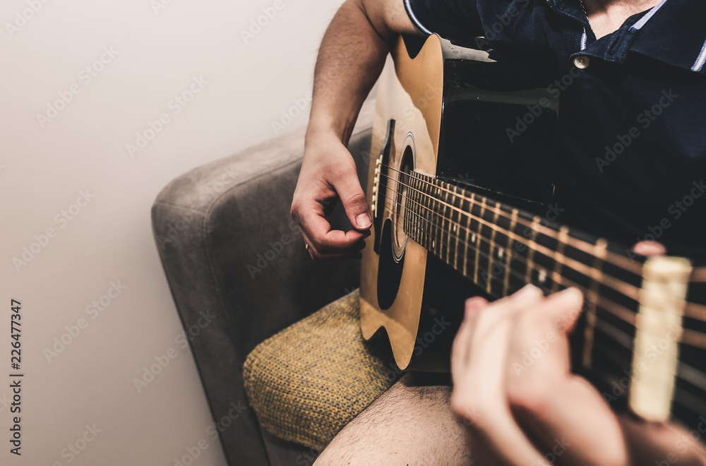 家里的男人在弹吉他。男人们的手在琴弦上弹奏和弦。音乐造就了人生