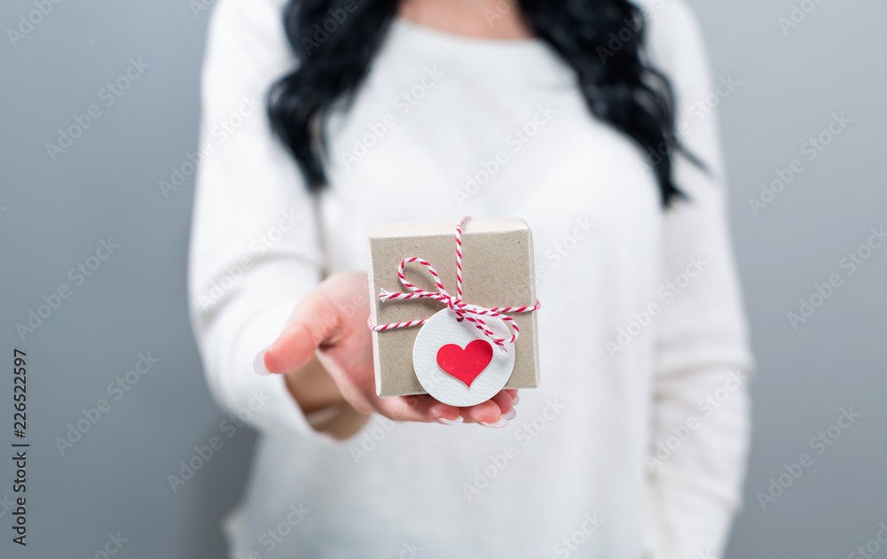 Woman with a gift box on a gray background