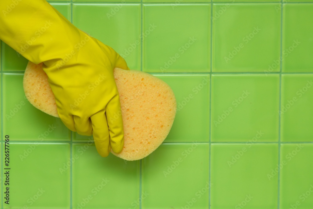 Hand in Rubber Glove Holding an Yellow Sponge and Cleaning Tiles