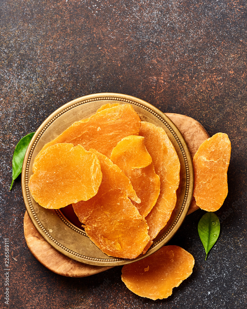 Dried mango slices. Top view of candied fruits on brown background.