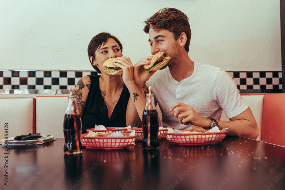 Man and woman eating burgers at a restaurant