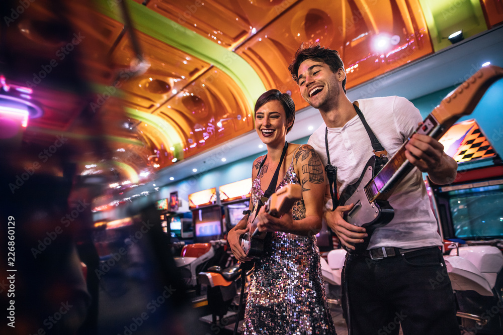 Smiling man and woman playing the guitar game at a gaming arcade