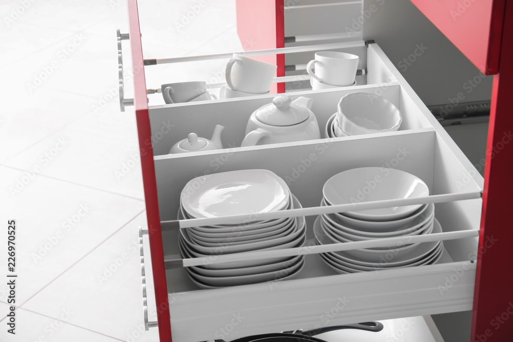 Set of clean tableware in kitchen drawer