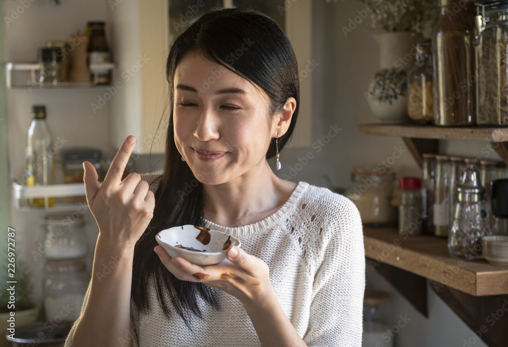 女人从杯子里品尝巧克力酱