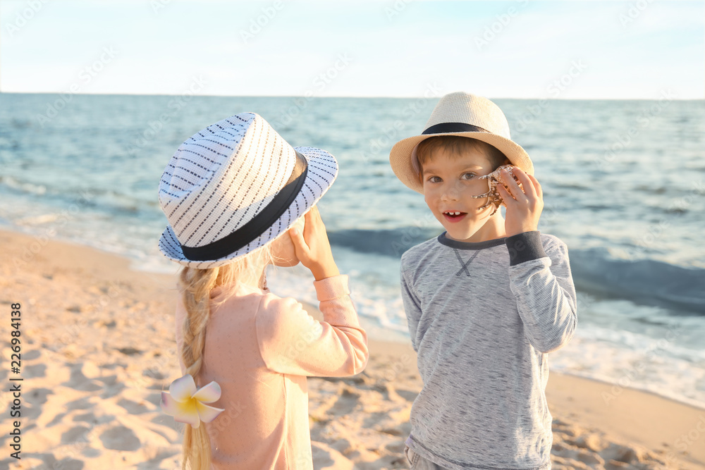 Cute little children playing with sea shells on beach