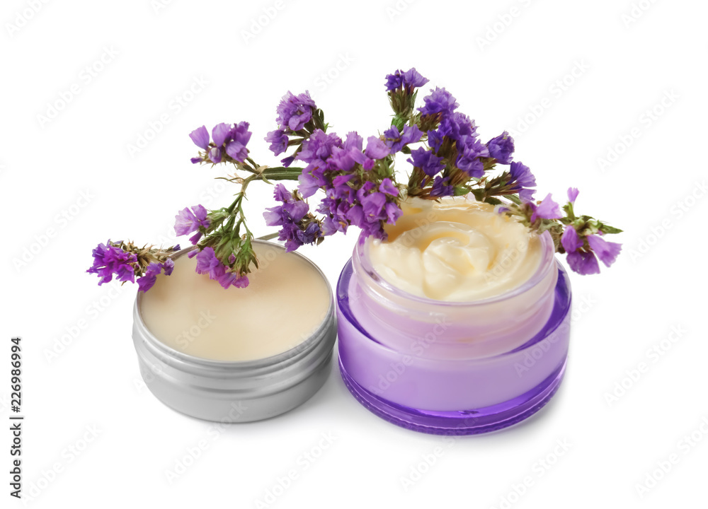 Jars with body cream and flowers on white background